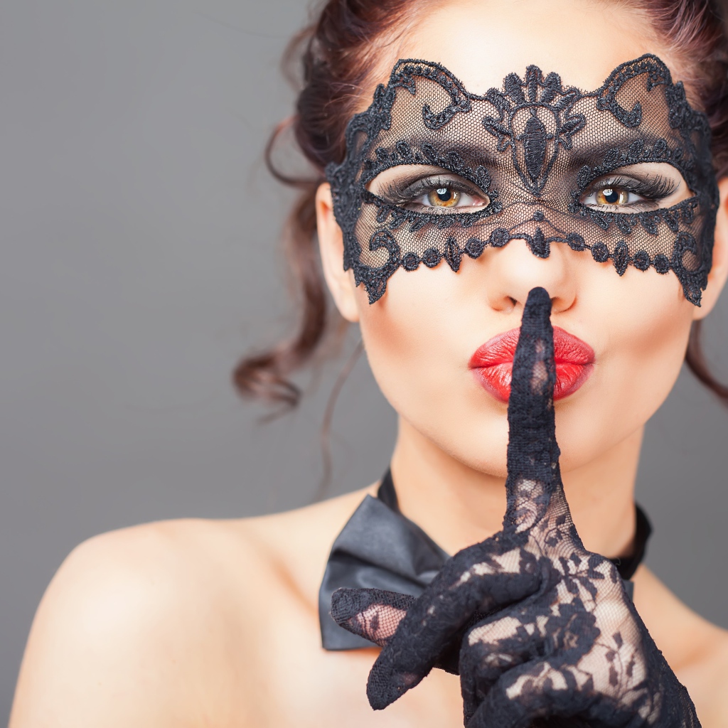 Девушка в черной маске с рукой в перчатке у лица