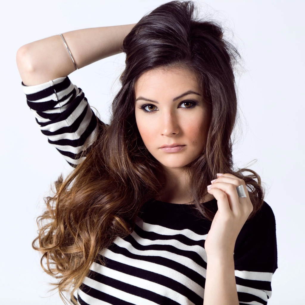 Девушка в полосатом свитере с рукой в волосах на белом фоне