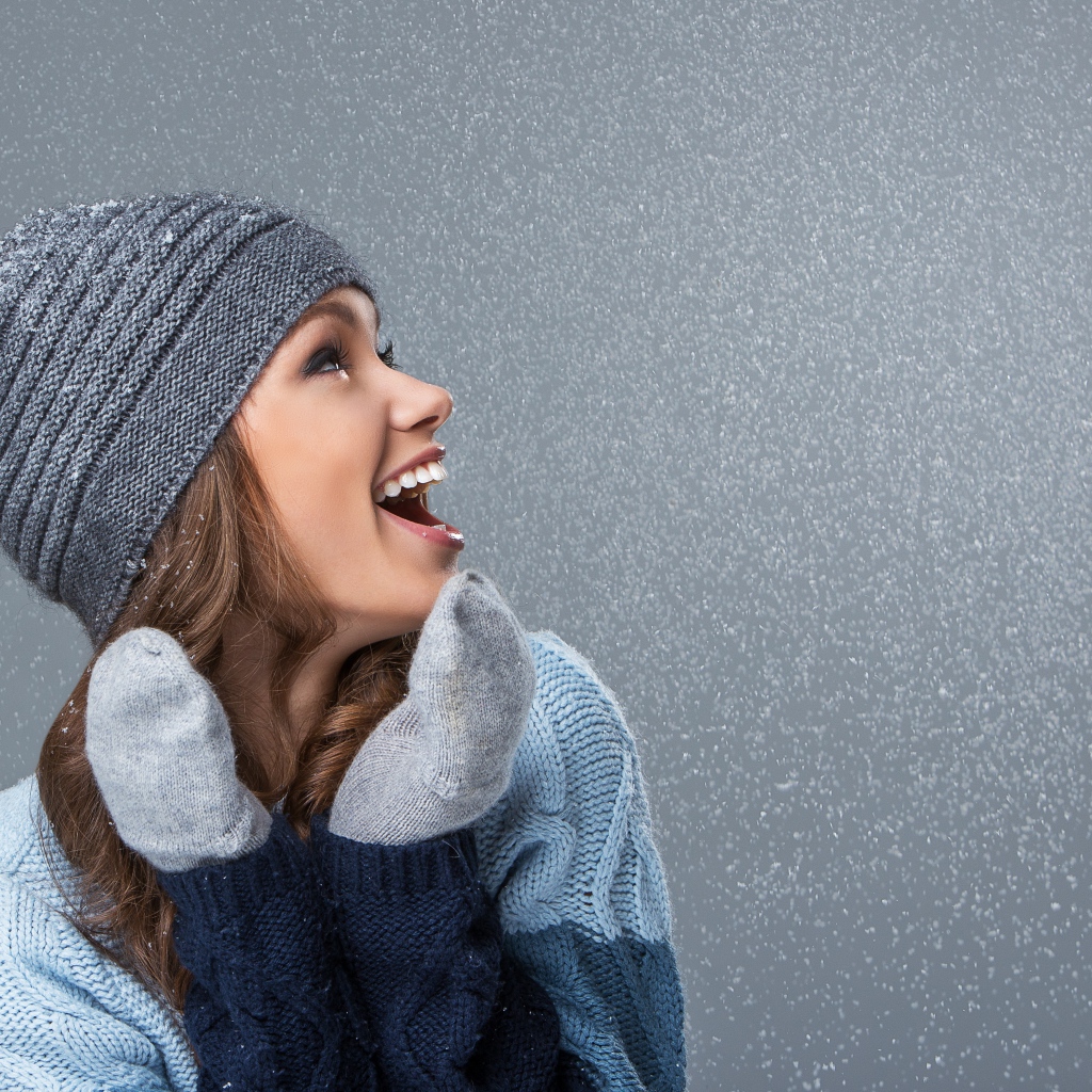 Девушка в теплой шапке на сером фоне