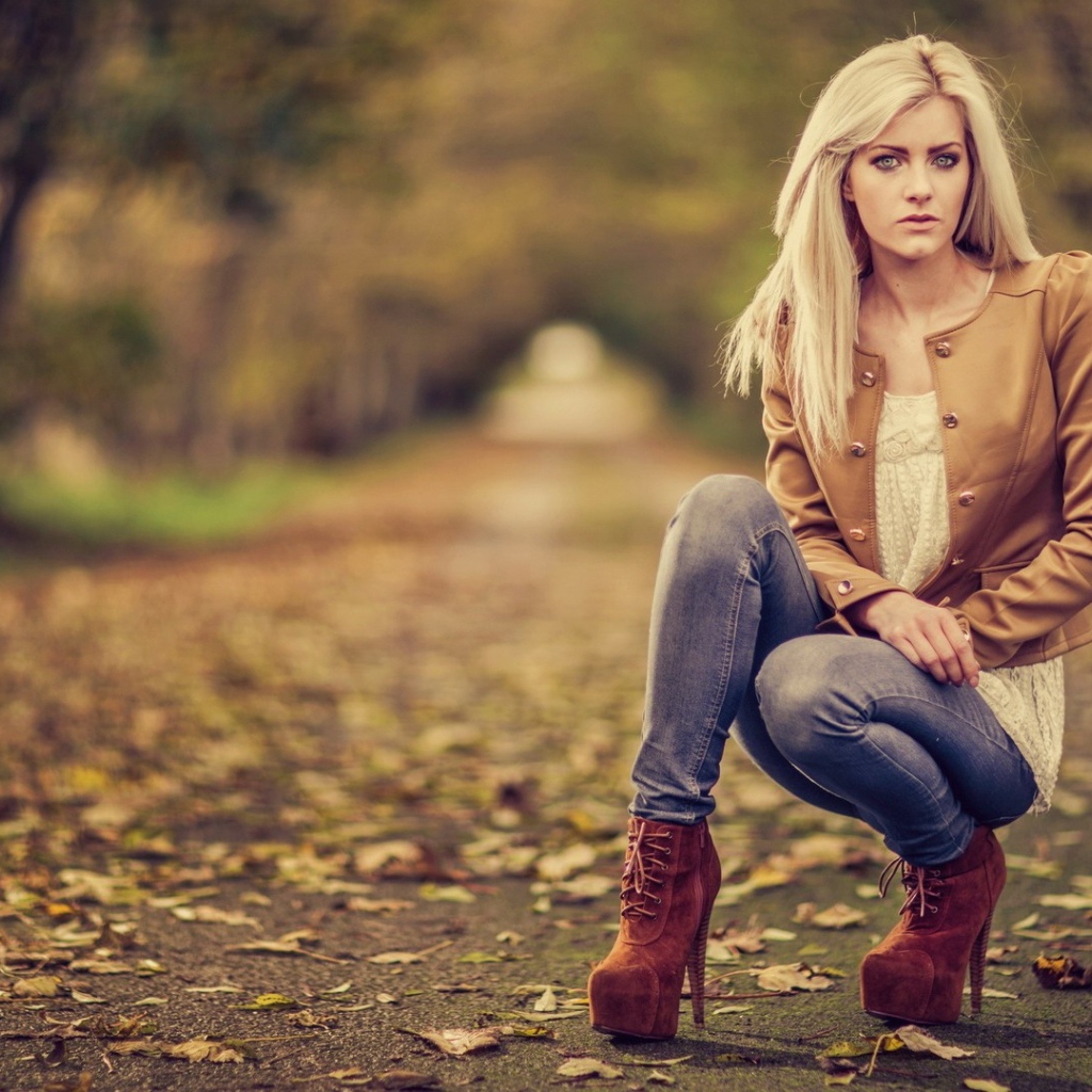 Девушка на высоких каблуках сидит на корточках в парке