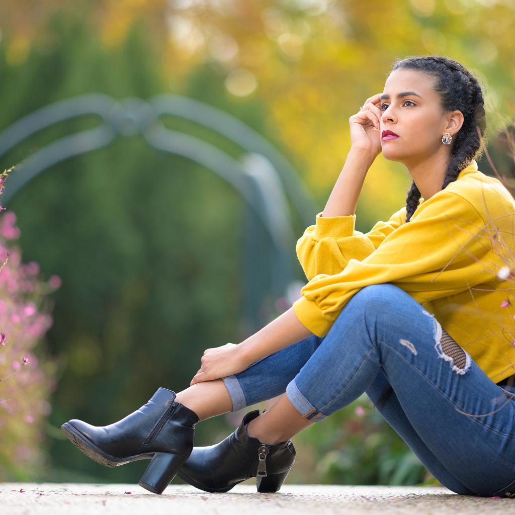 Девушка в джинсах сидит на земле 