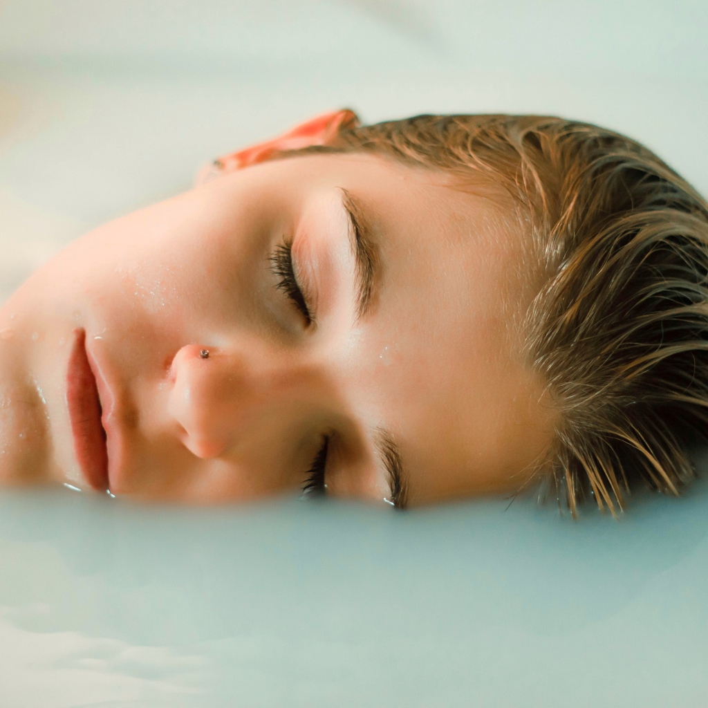 Девушка лежит с закрытыми глазами в ванной