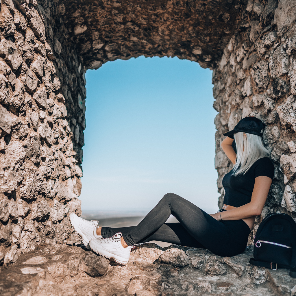 Девушка сидит в окне старого здания 