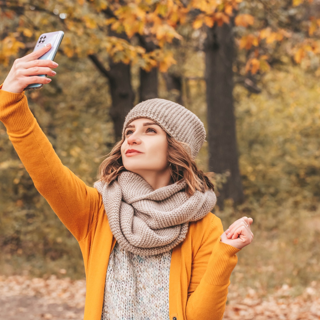 Девушка делает селфи на улице осенью 
