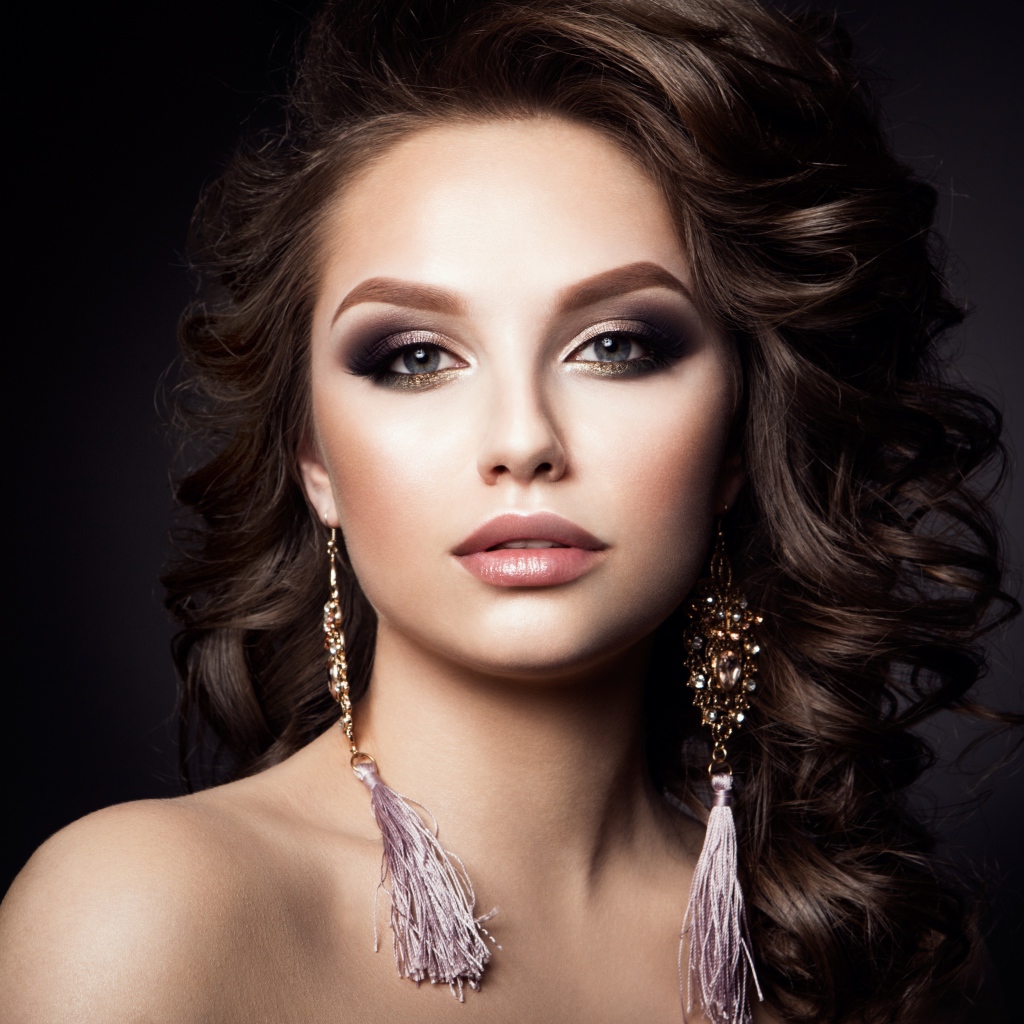 Девушка с прической с красивыми сережками на сером фоне 