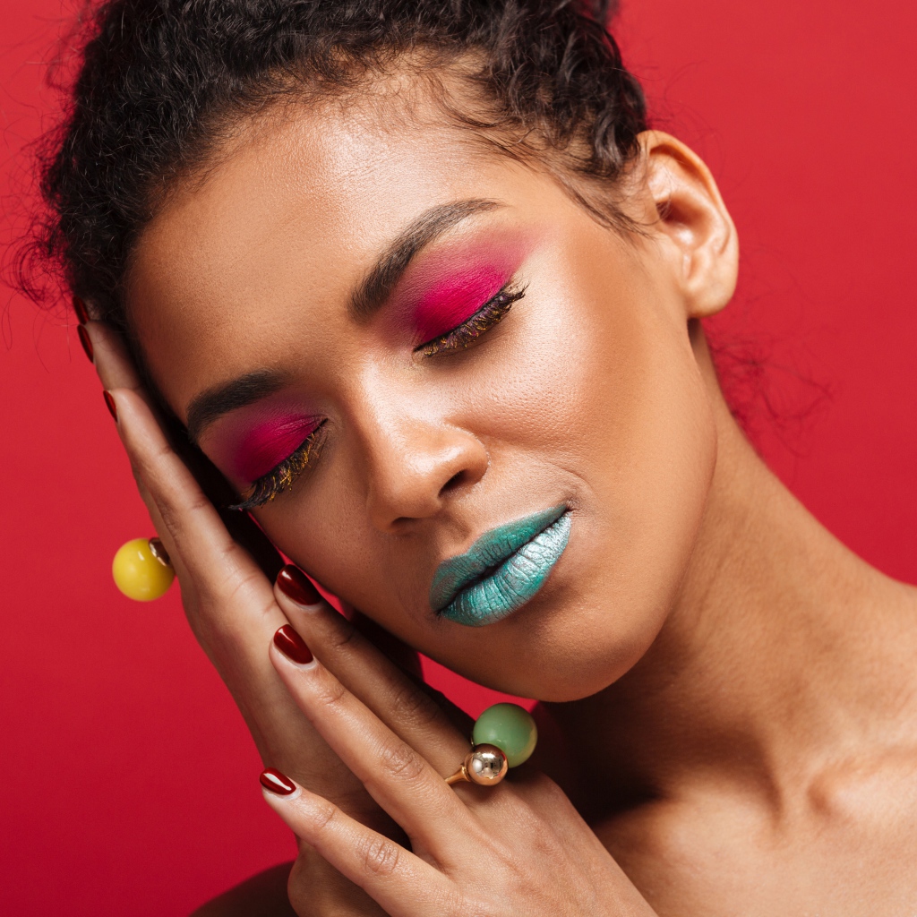 Девушка с ярким макияжем на красном фоне