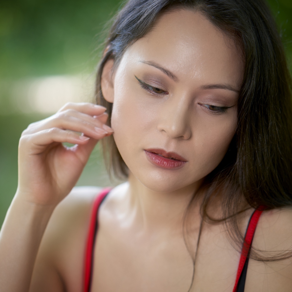 Девушка с опущенными глазами с рукой у лица