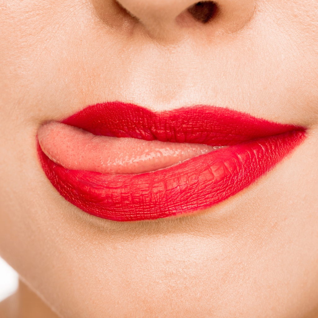 Девушка с  красными губами показывает язык