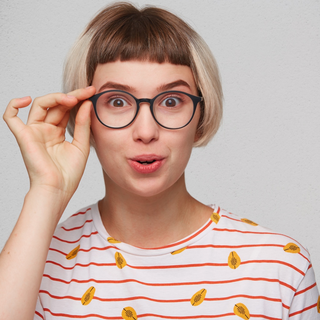 Девушка с короткой стрижкой поправляет очки 