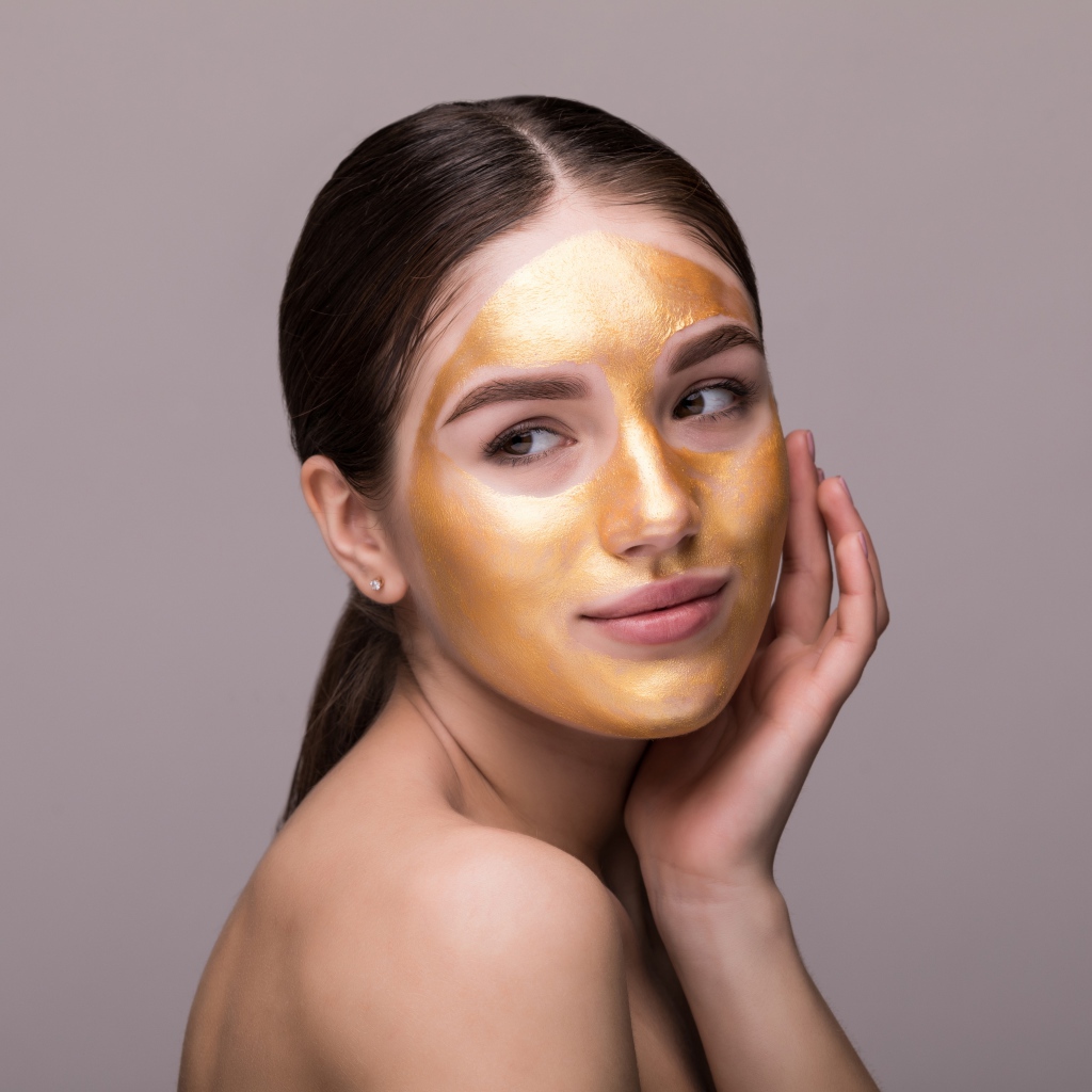 Золотая маска на лице у молодой девушки 