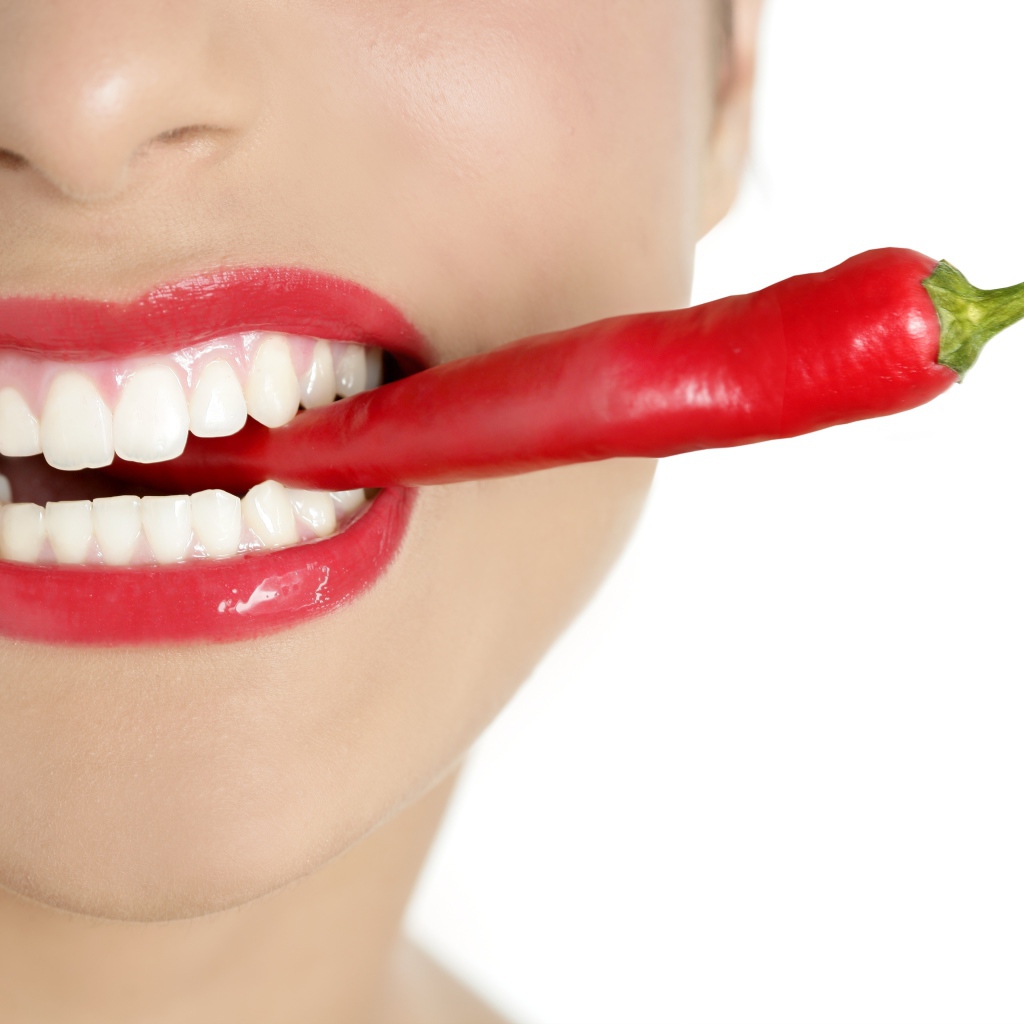 Острый перец во рту у девушки с красивыми белыми зубами 