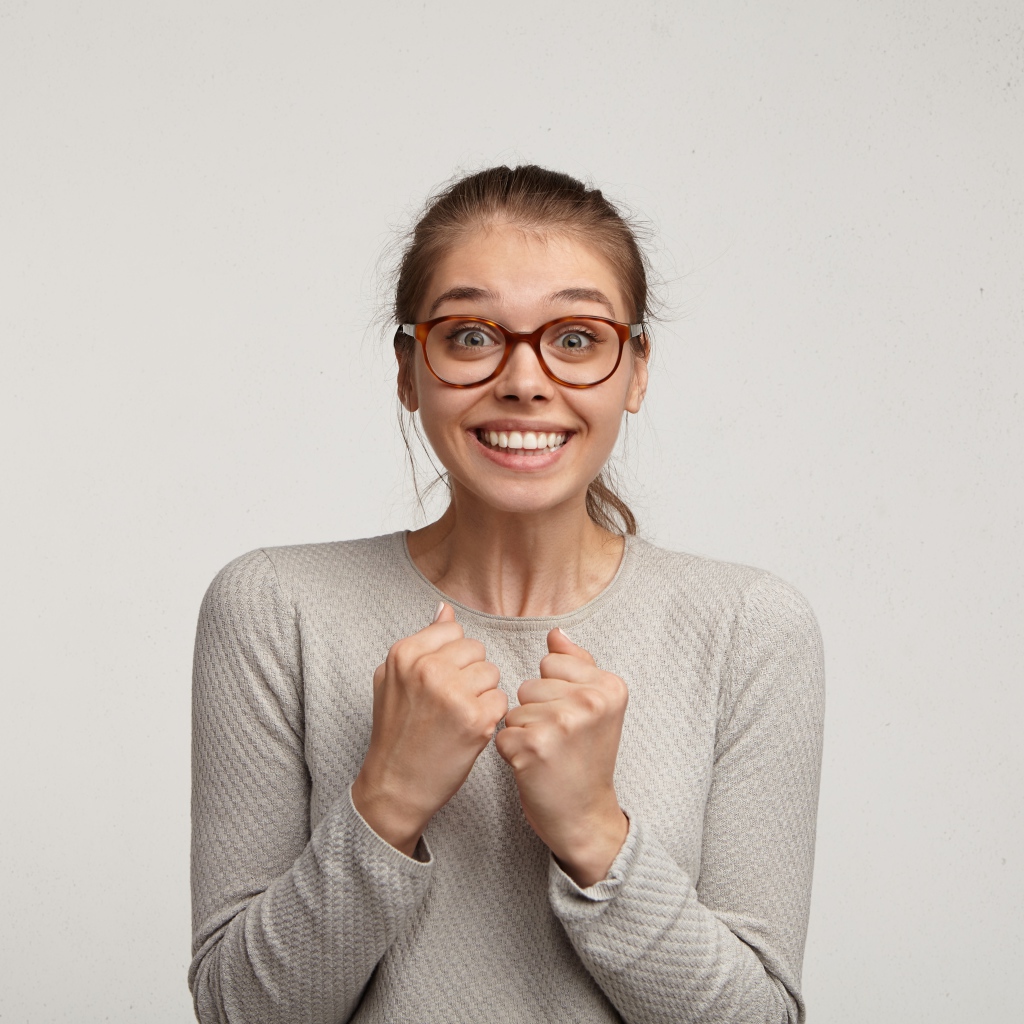 Радостная девушка в очках для зрения на сером фоне 