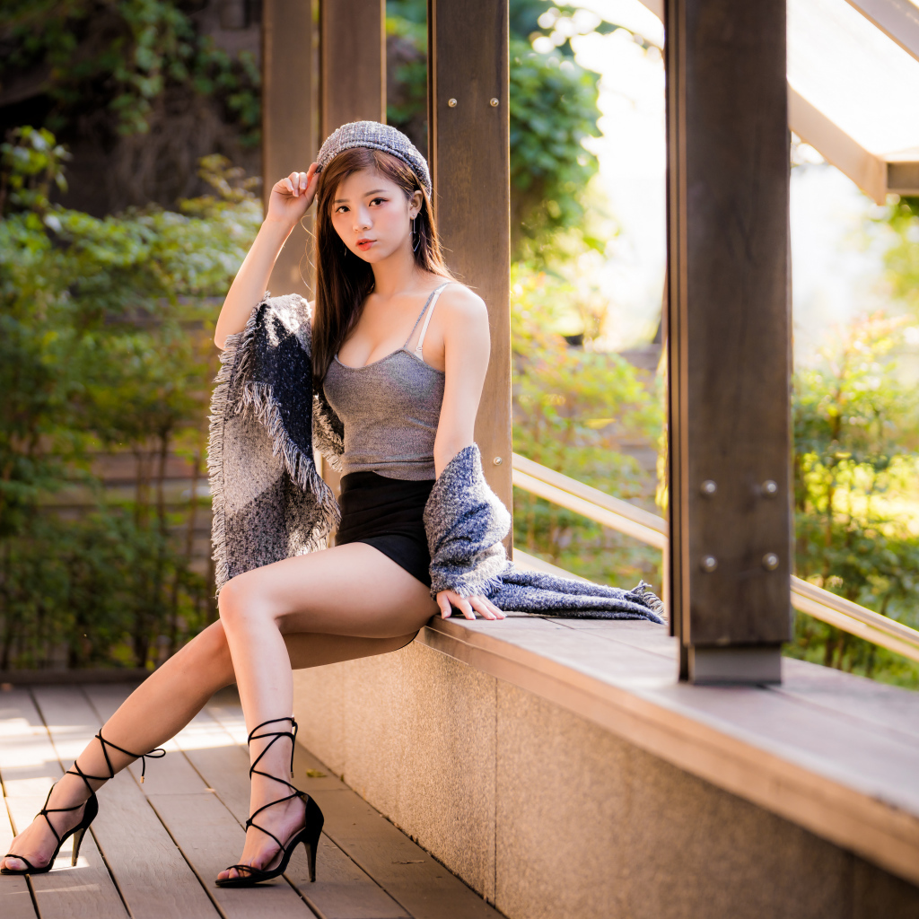Длинноногая азиатка сидит на окне 