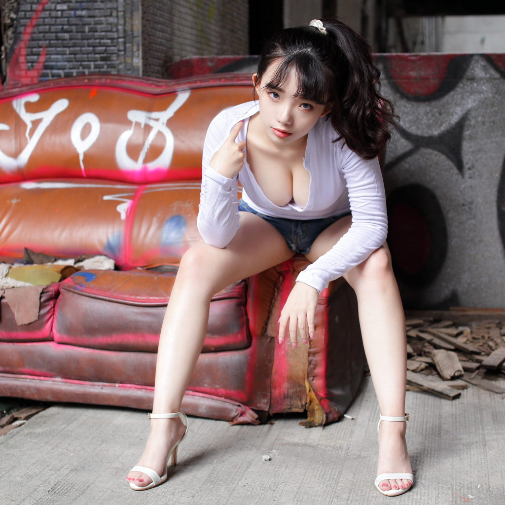 Длинноволосая девушка азиатка сидит на старом диване