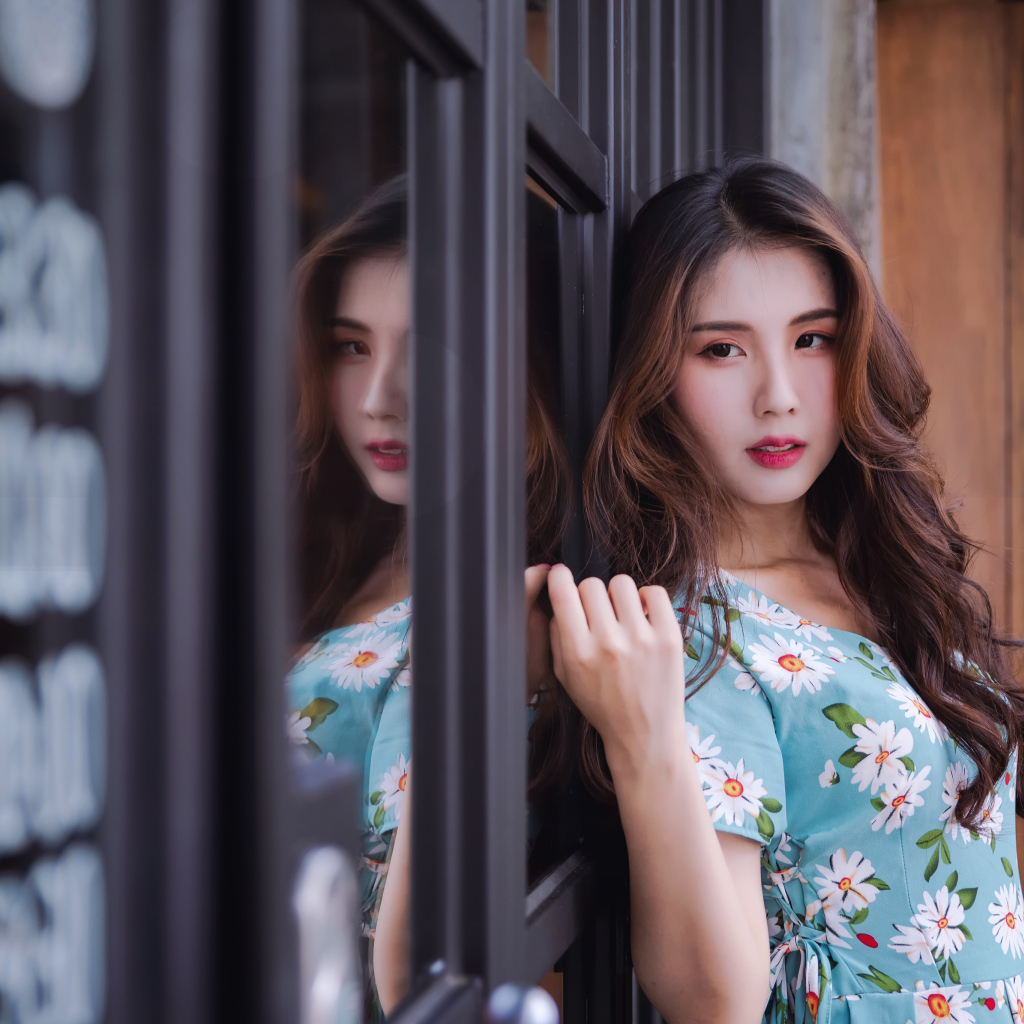 Длинноволосая девушка азиатка стоит у окна