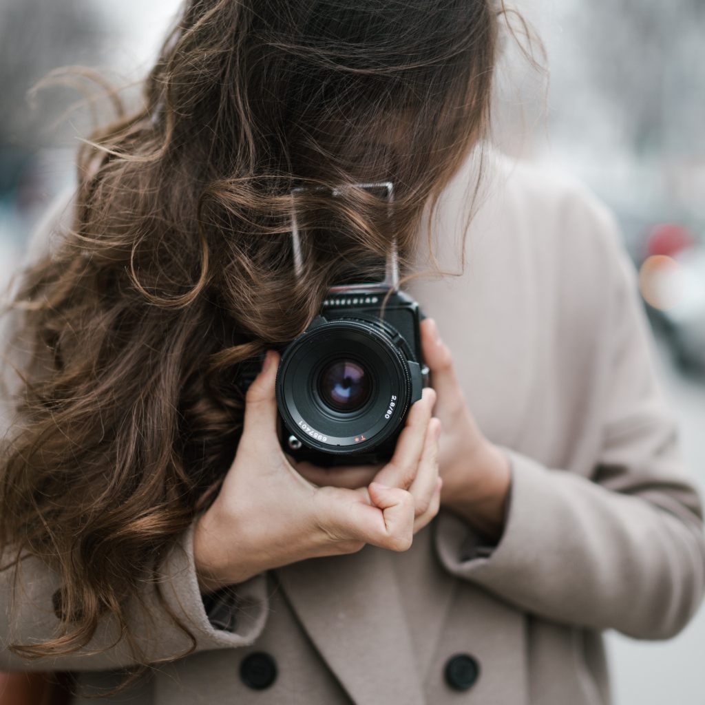 Длинноволосая девушка с фотоаппаратом в руках 