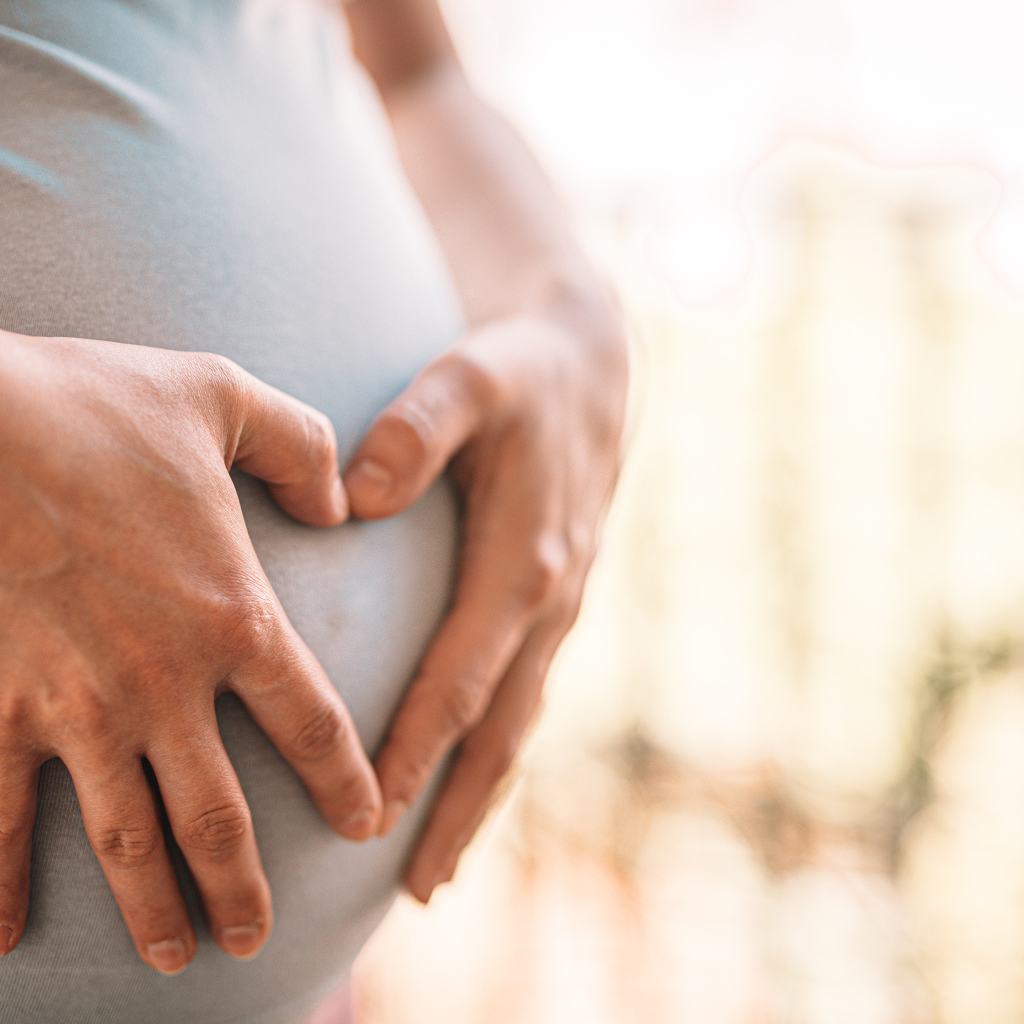 Беременная женщина держит руки на животе 