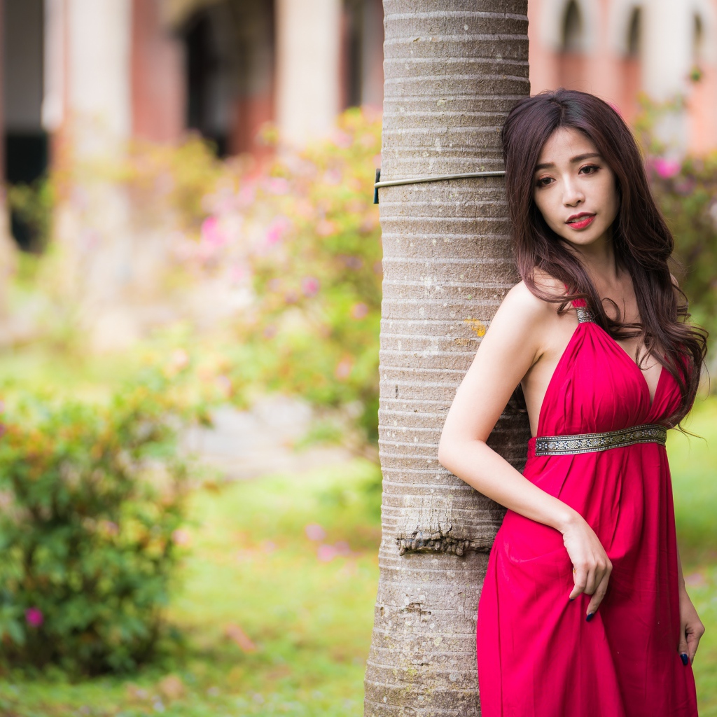 Стройная азиатка в красном платье у дерева 