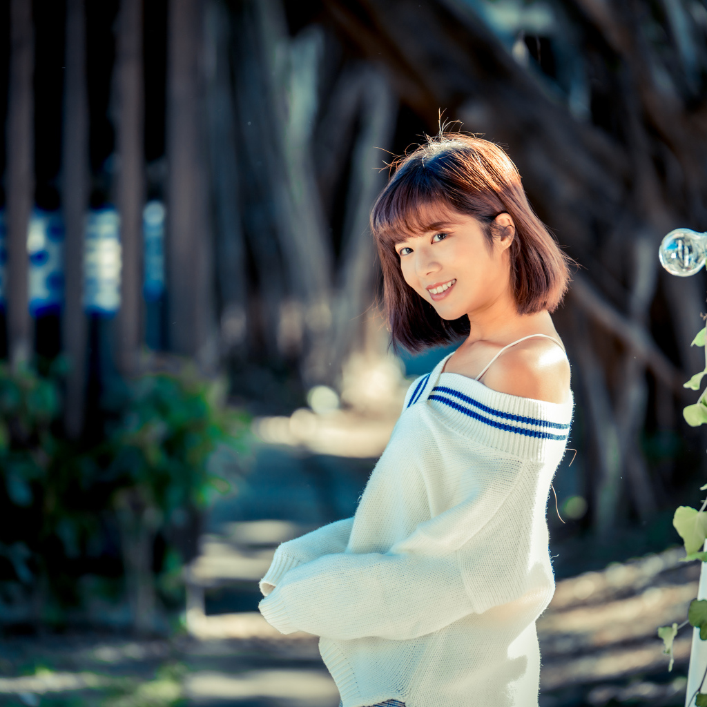 Улыбающаяся девушка азиатка в белом свитере 