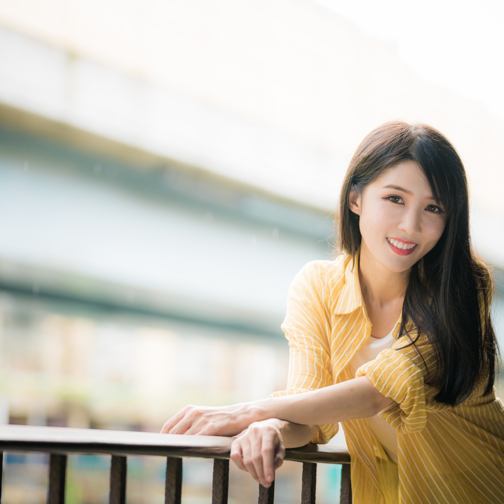 Улыбающаяся азиатка в желтой полосатой рубашке