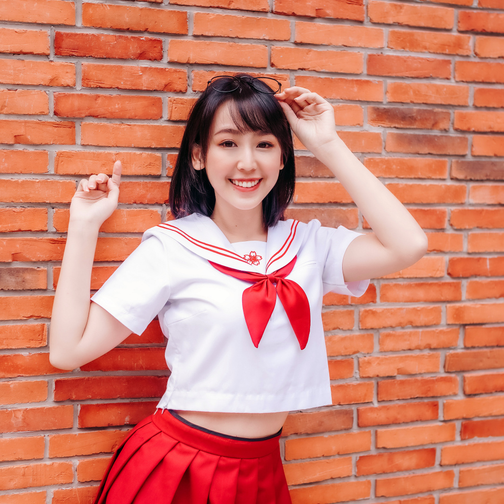 Улыбающаяся азиатка стоит у стены 