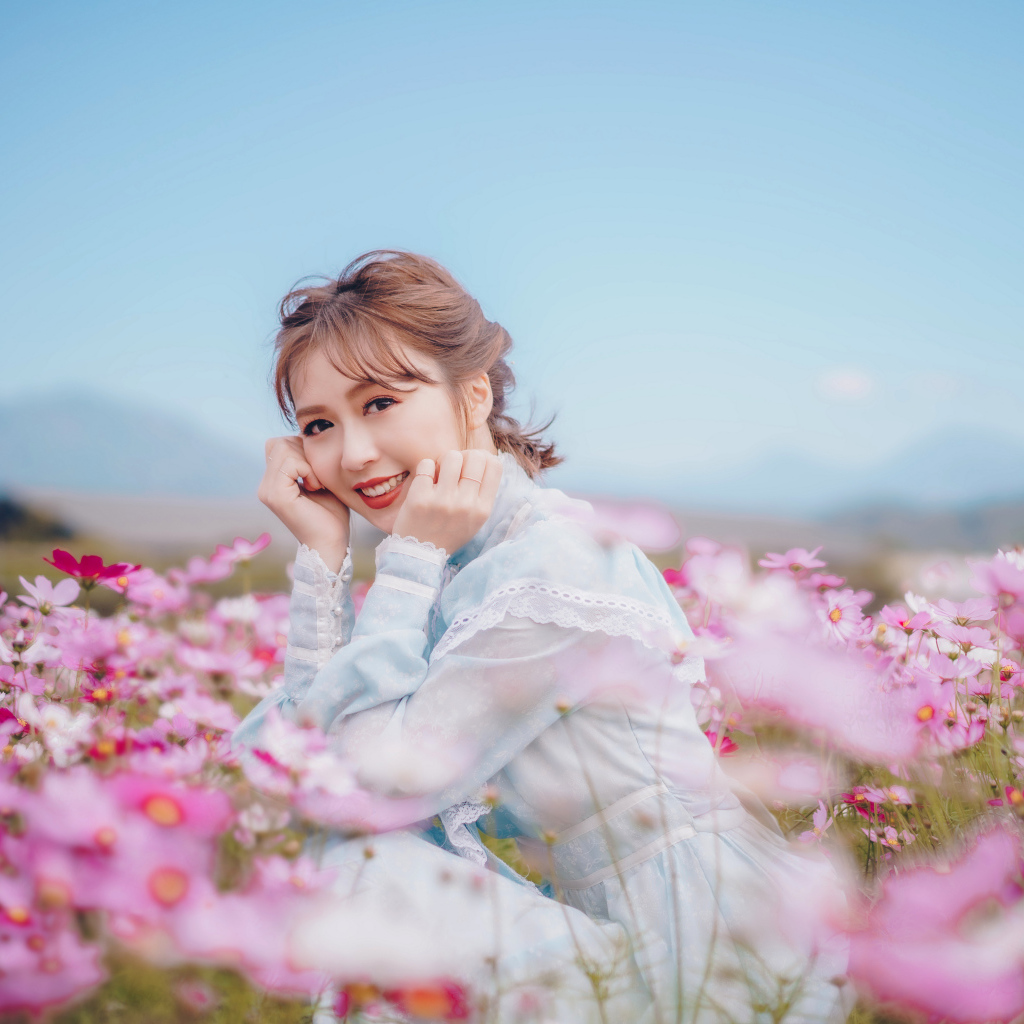 Улыбающаяся девушка азиатка на поле с цветами космеи 