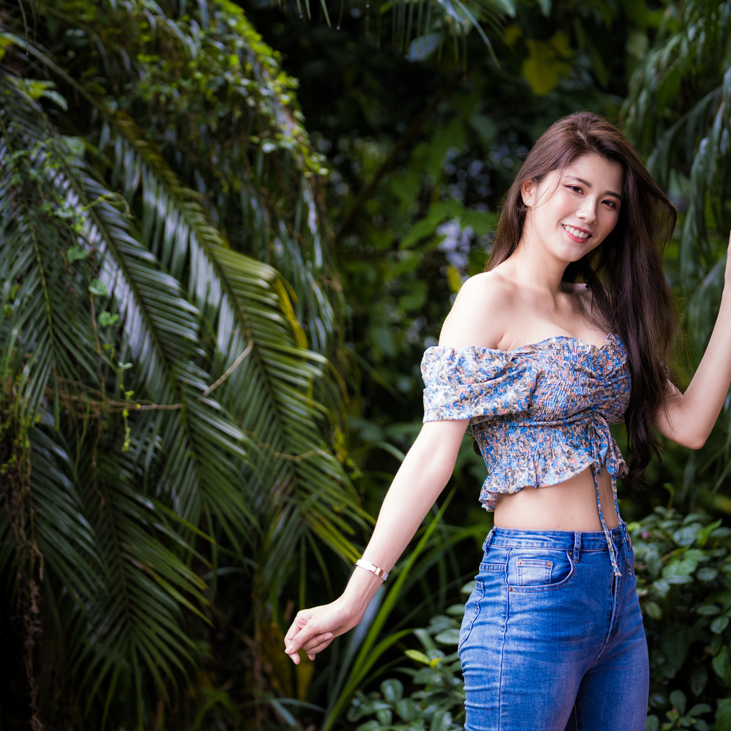 Улыбающаяся азиатка на фоне зеленых листьев