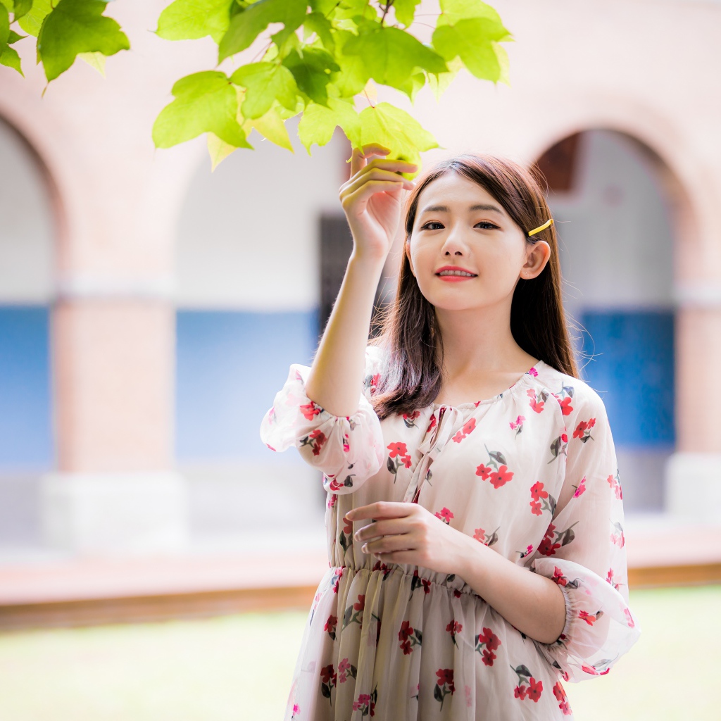 Улыбающаяся девушка в платье у дерева 