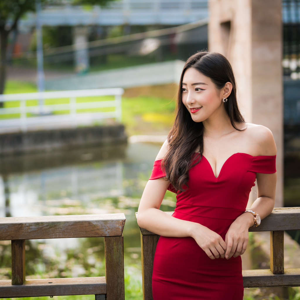 Улыбающаяся девушка в красном платье у перил 