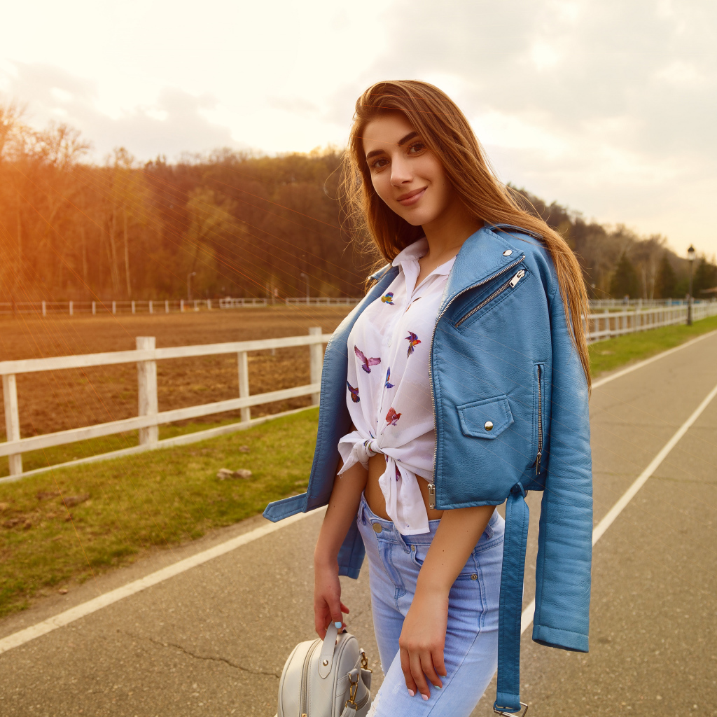 Улыбающаяся девушка в синей кожаной куртке на дороге 