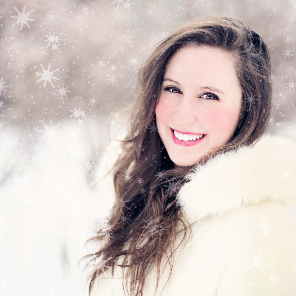 Улыбающаяся девушка в белой шубе на улице зимой 