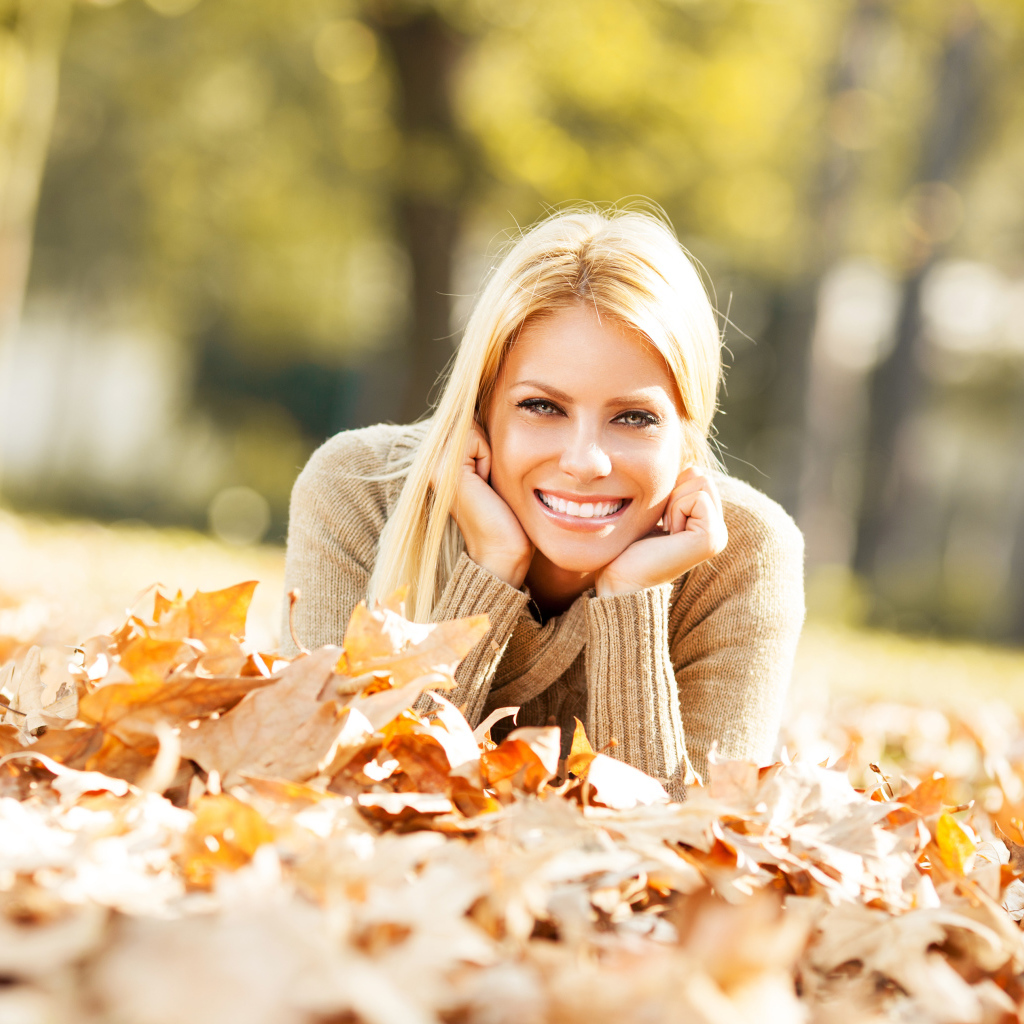 Улыбающаяся девушка лежит на сухой опавшей листве