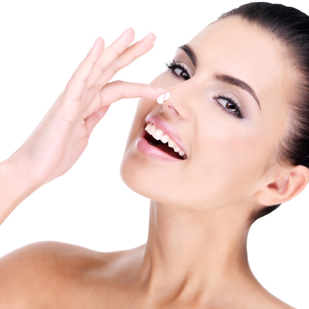 Улыбающаяся девушка мажет крем на нос 