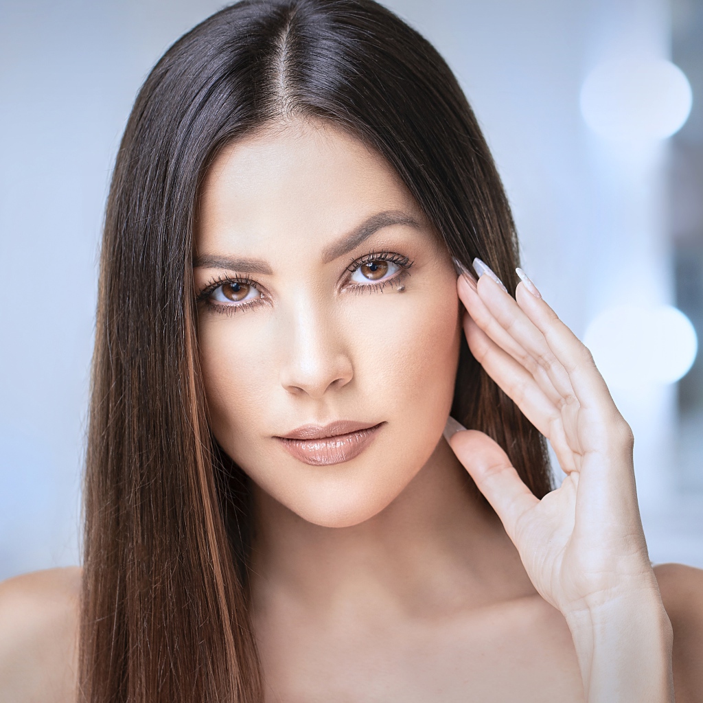 Стильная кареглазая длинноволосая брюнетка с рукой у лица