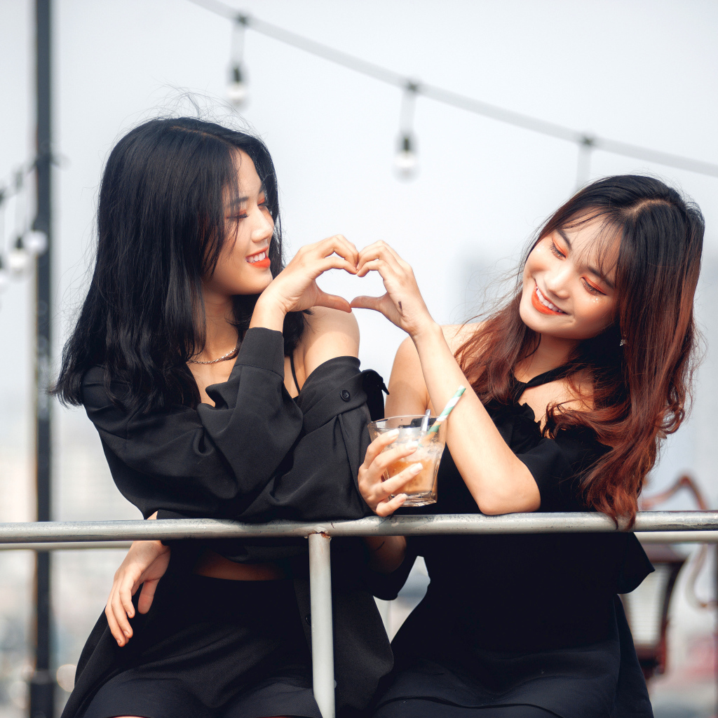 Две девушки азиатки делают сердце руками 
