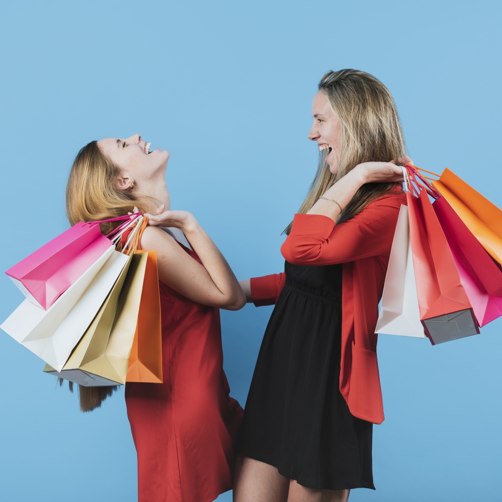 Две девушки с покупками на голубом фоне