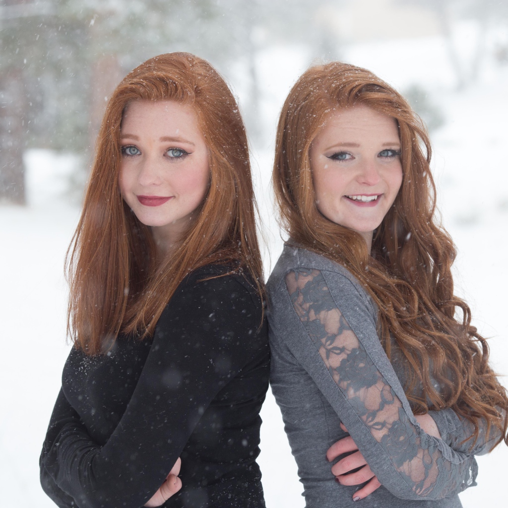 Две улыбающиеся рыжеволосые сестры на улице зимой 