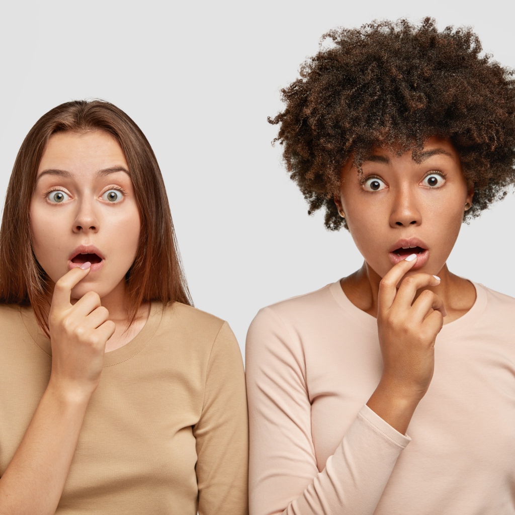 Две удивленные девушки на сером фоне 