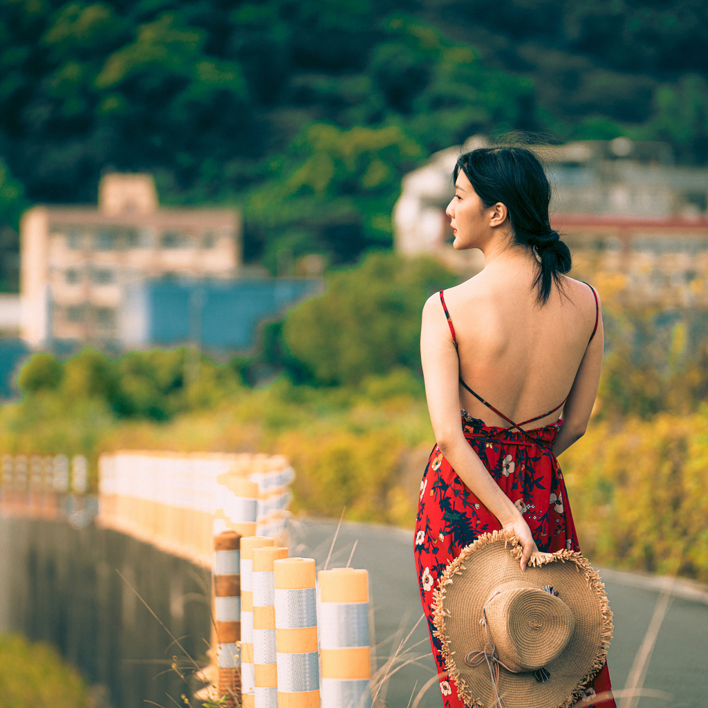 Молодая девушка азиатка в сарафане со шляпой в руке 