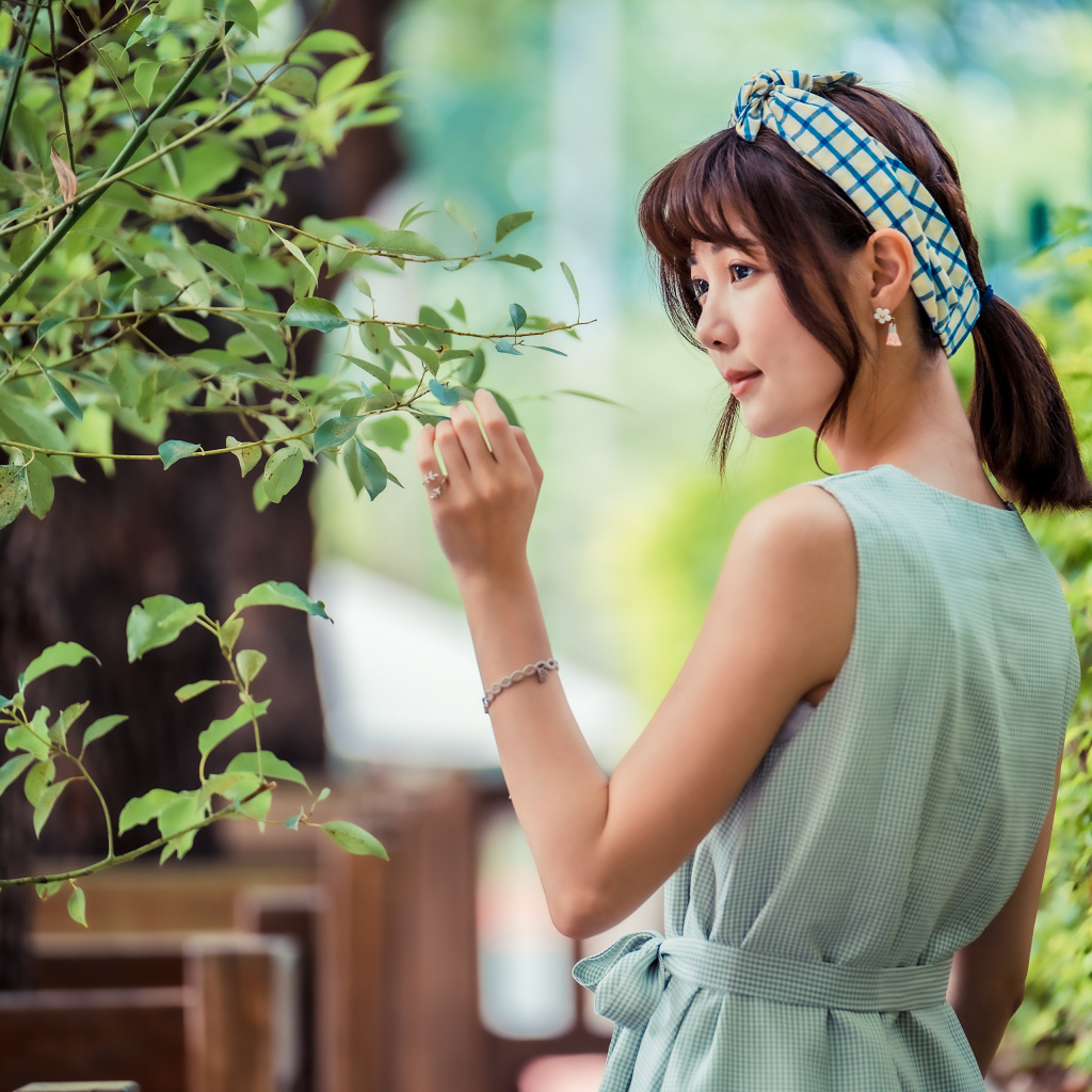 Молодая девушка азиатка с повязкой на голове у дерева 