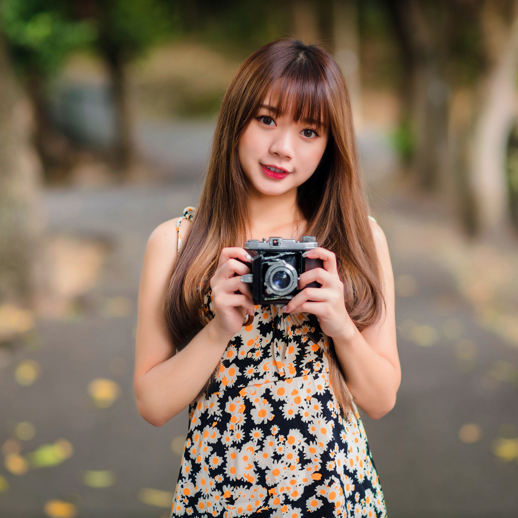 Молодая девушка азиатка с фотоаппаратом в руках 