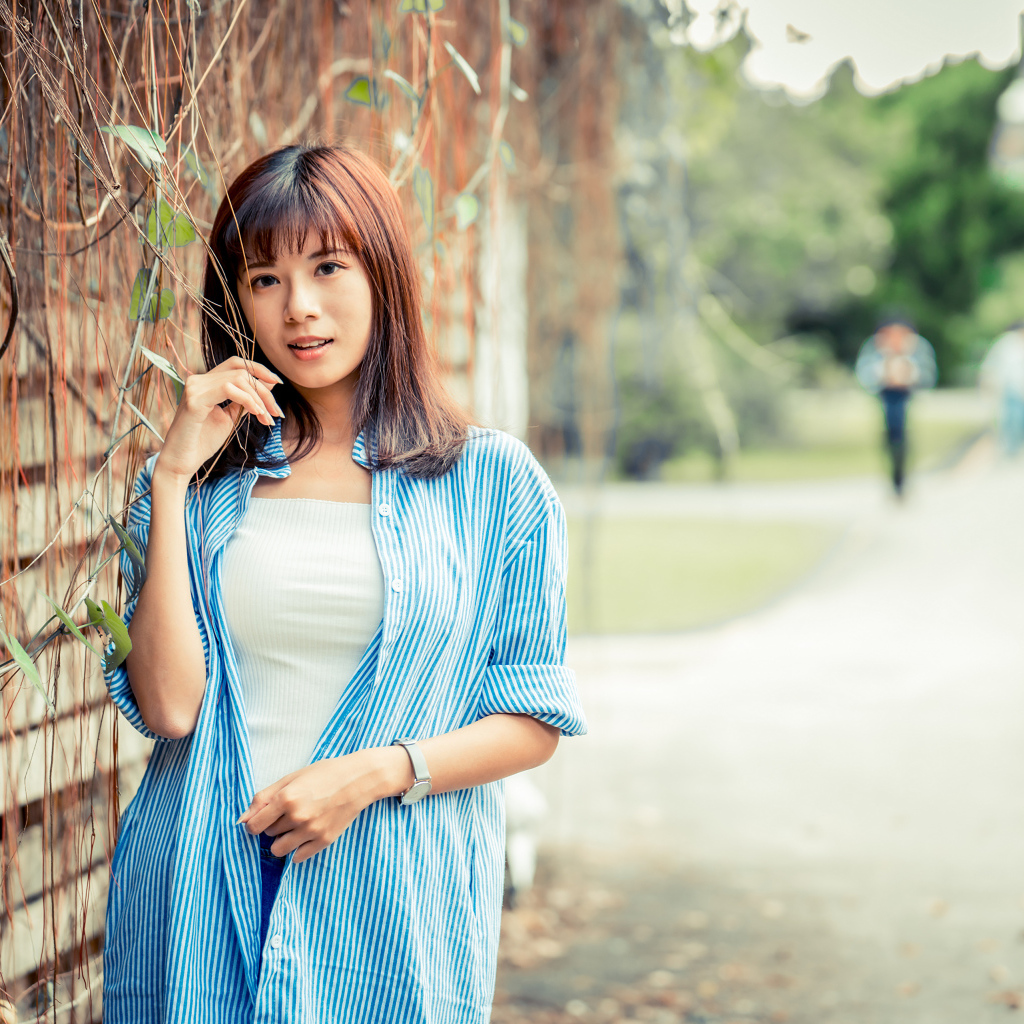 Молодая азиатка в рубашке у стены