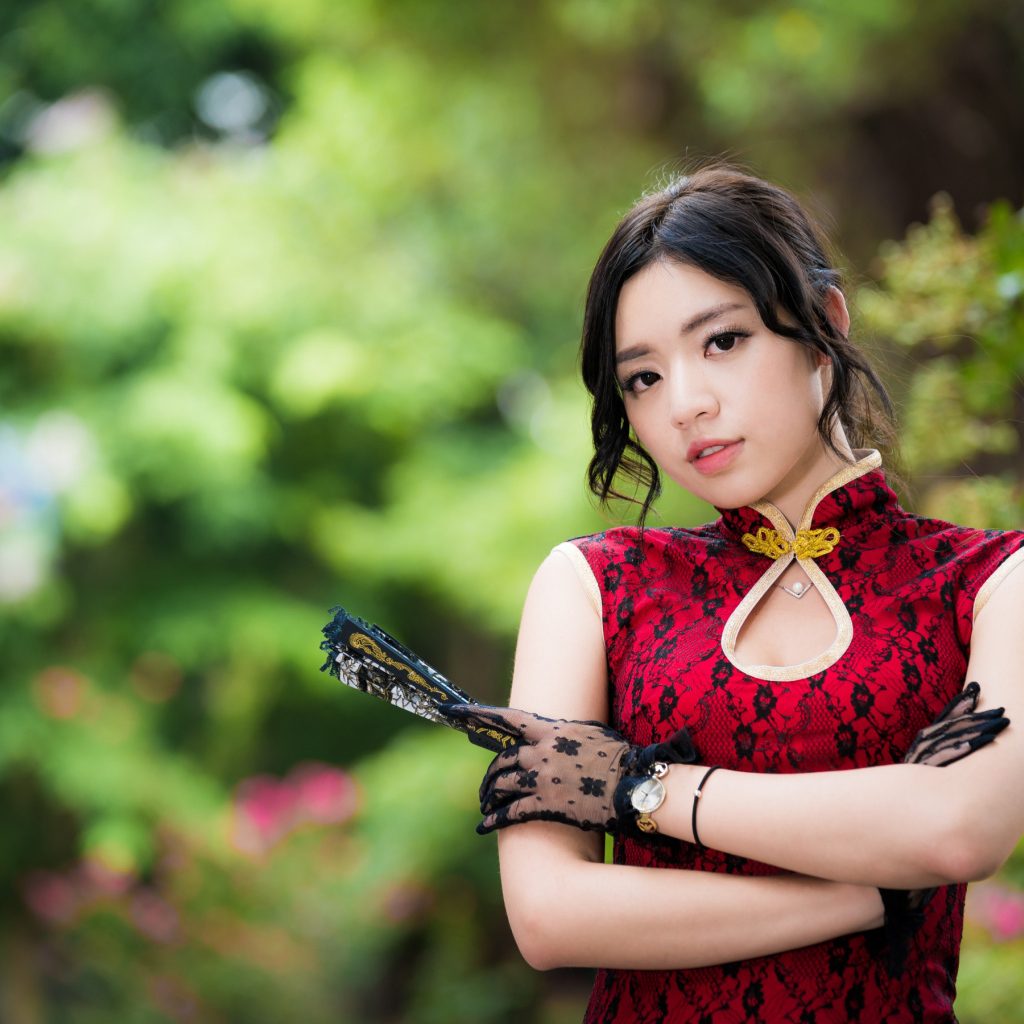 Молодая азиатка в красивом платье с веером в руке