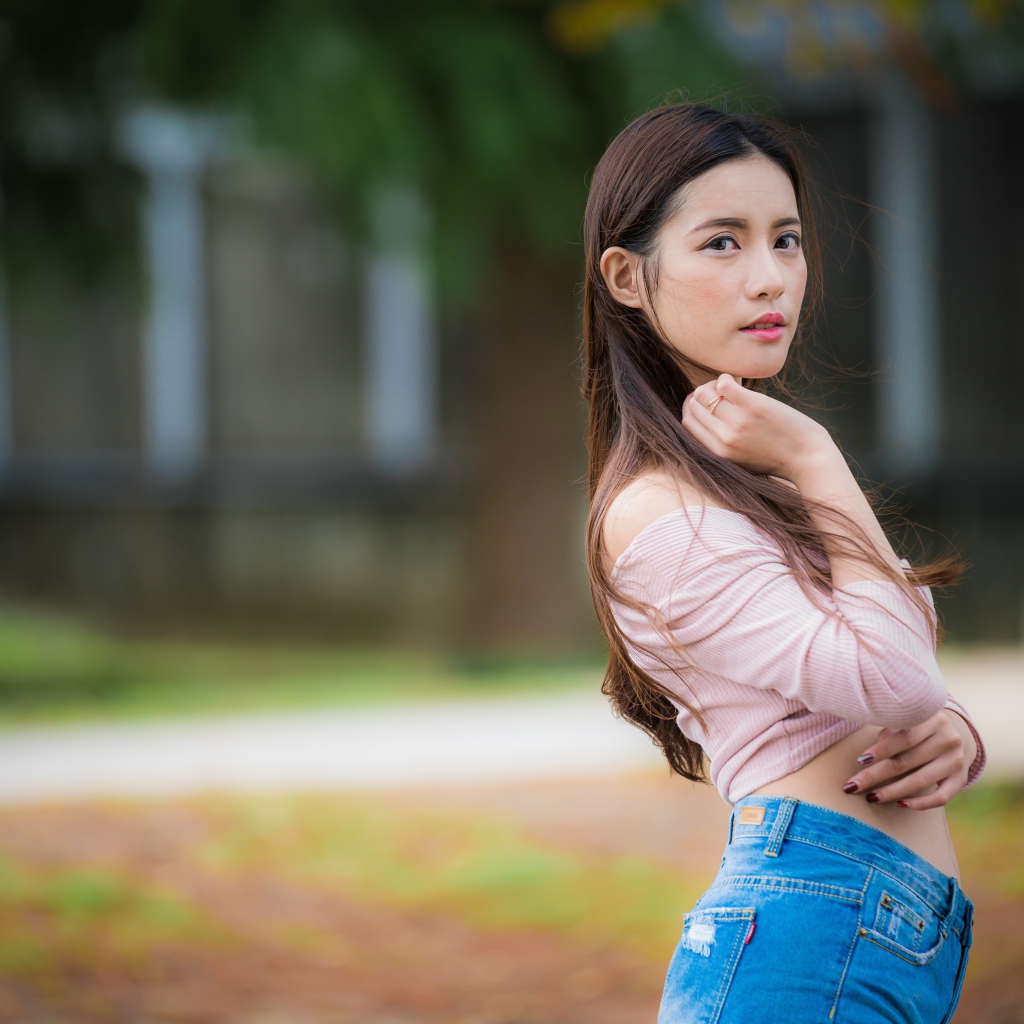 Молодая азиатка с длинными волосами в синих джинсах