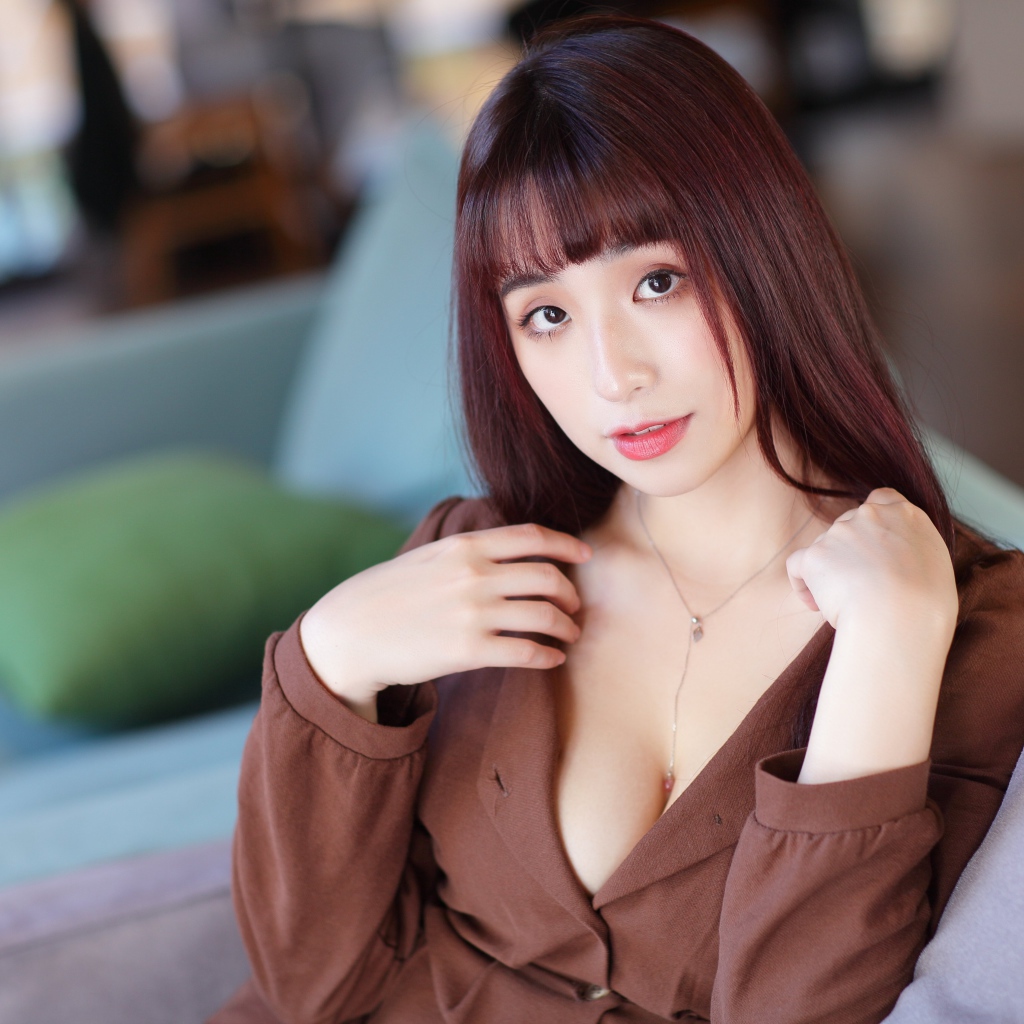 Молодая азиатка сидит на диване 