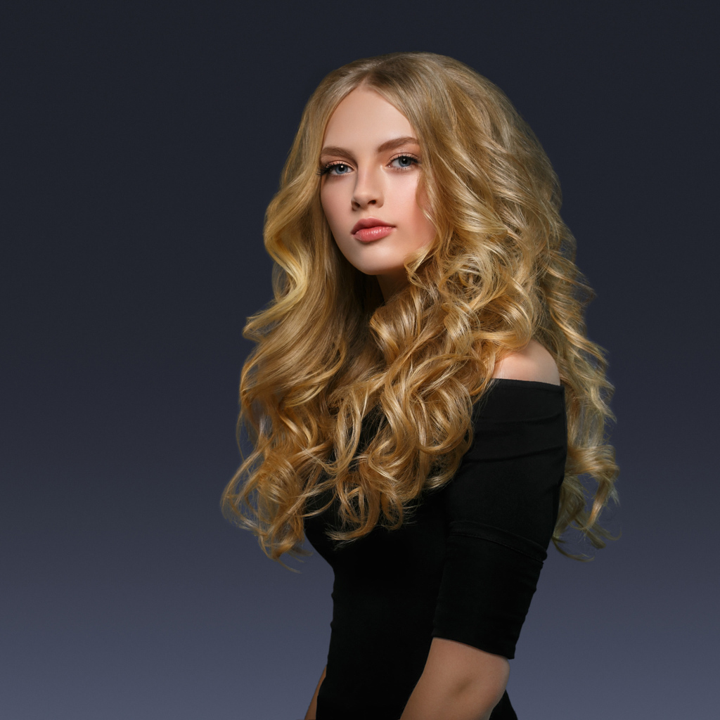 Молодая блондинка с красивыми длинными волосами в черном платье