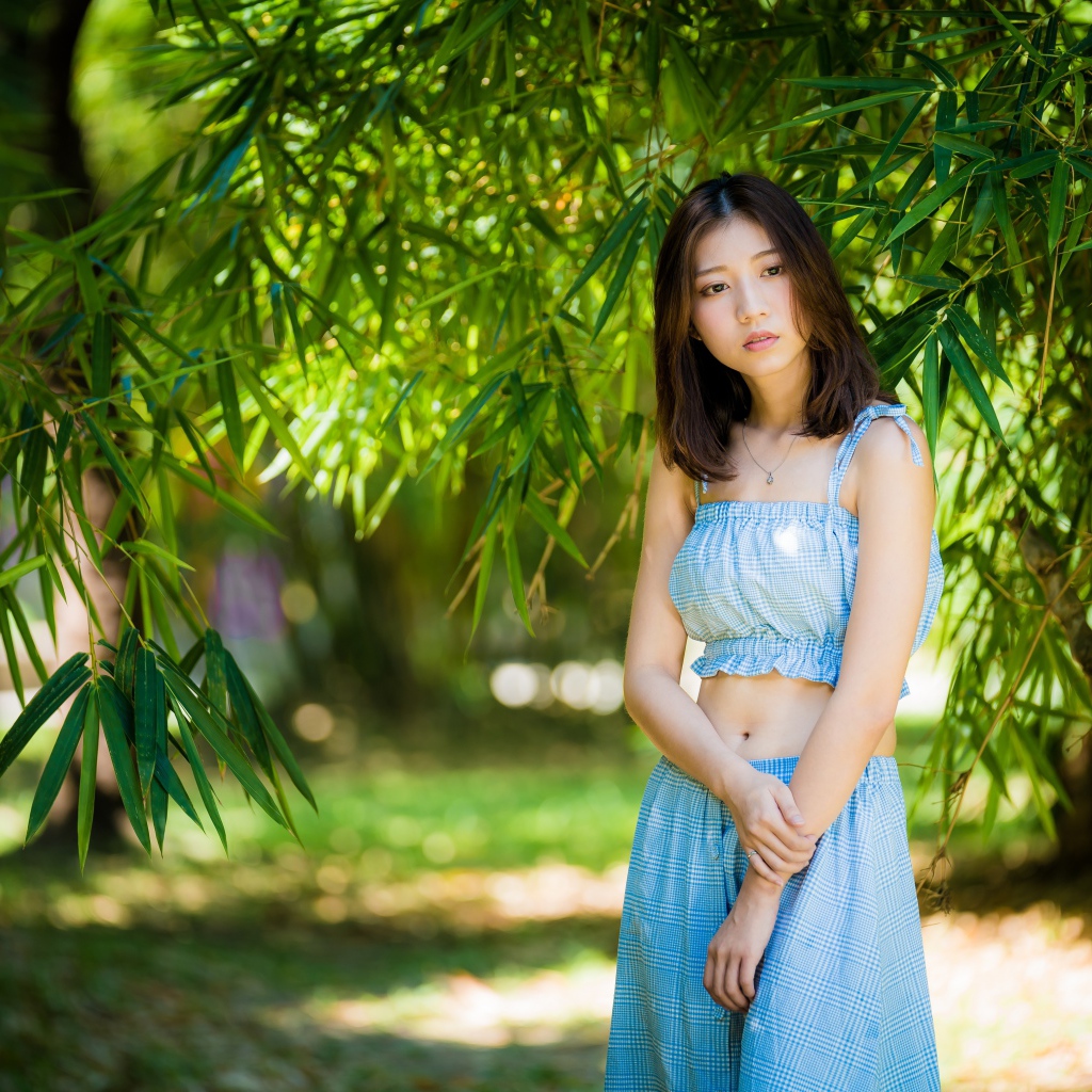 Молодая девушка в голубом костюме под деревом