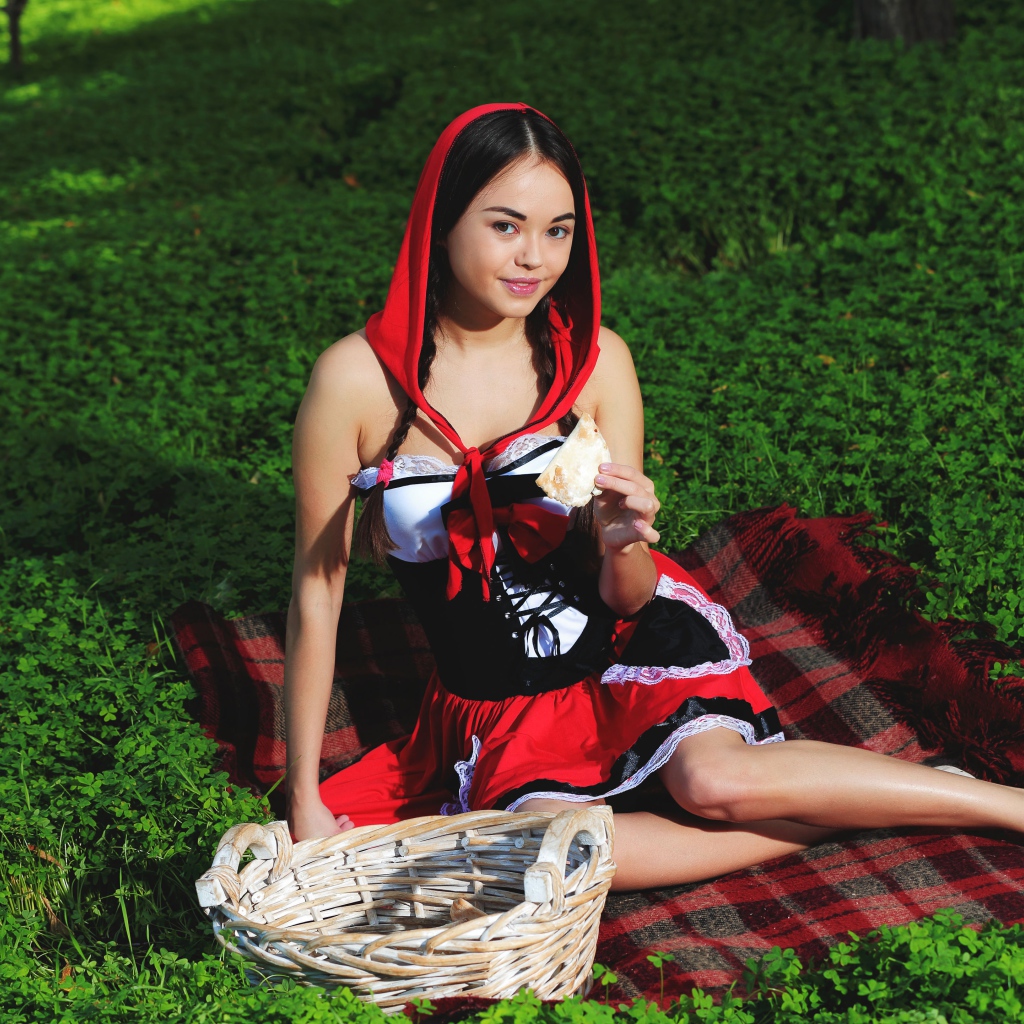 Молодая девушка в костюме сидит на траве, косплей