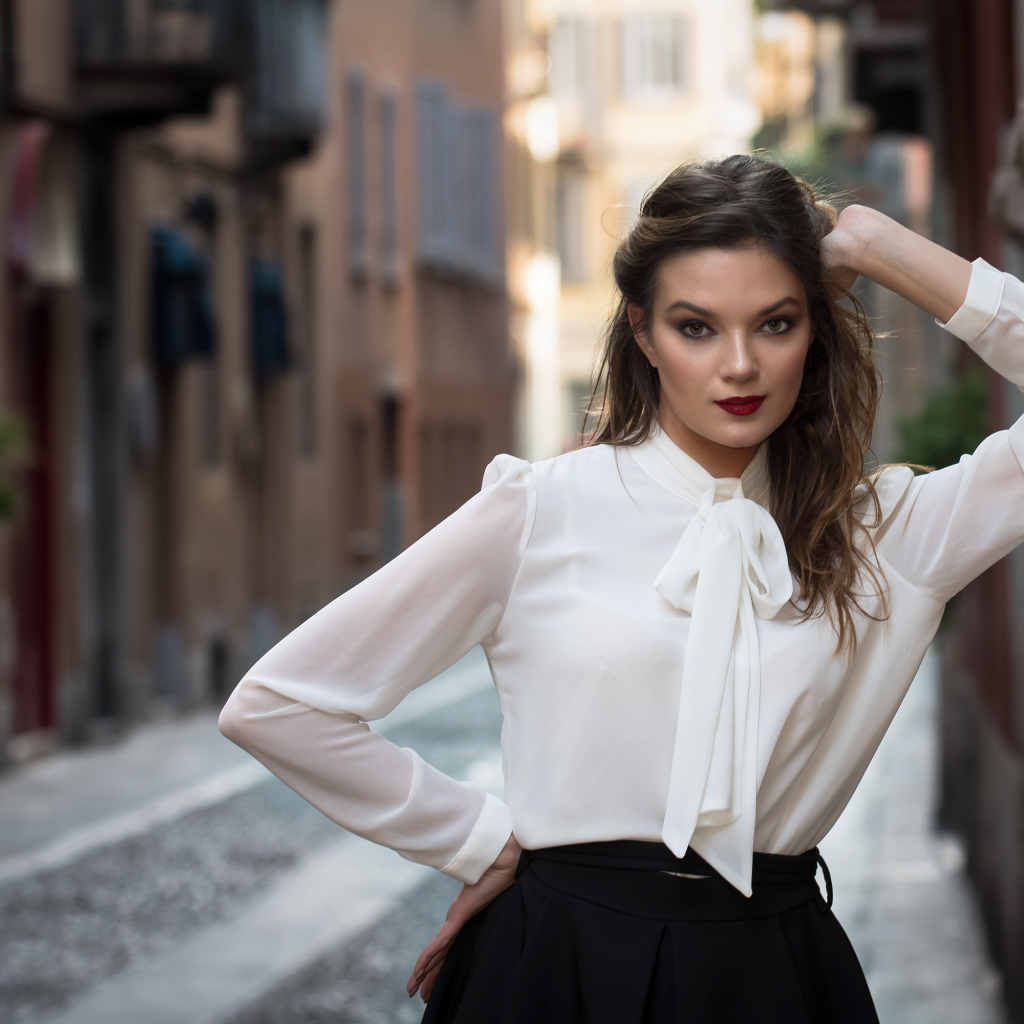 Молодая девушка в белой рубашке у стены