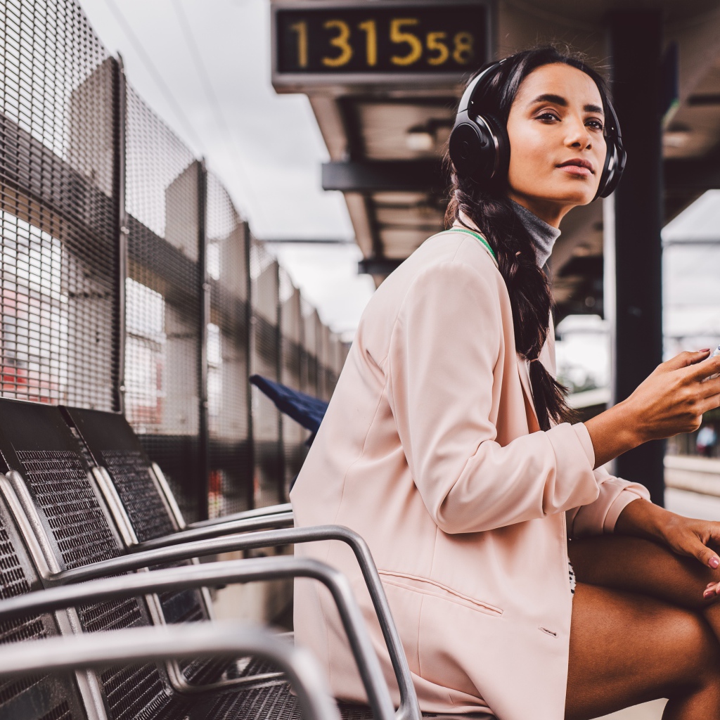 Young girl in headphones sits at a bus stop